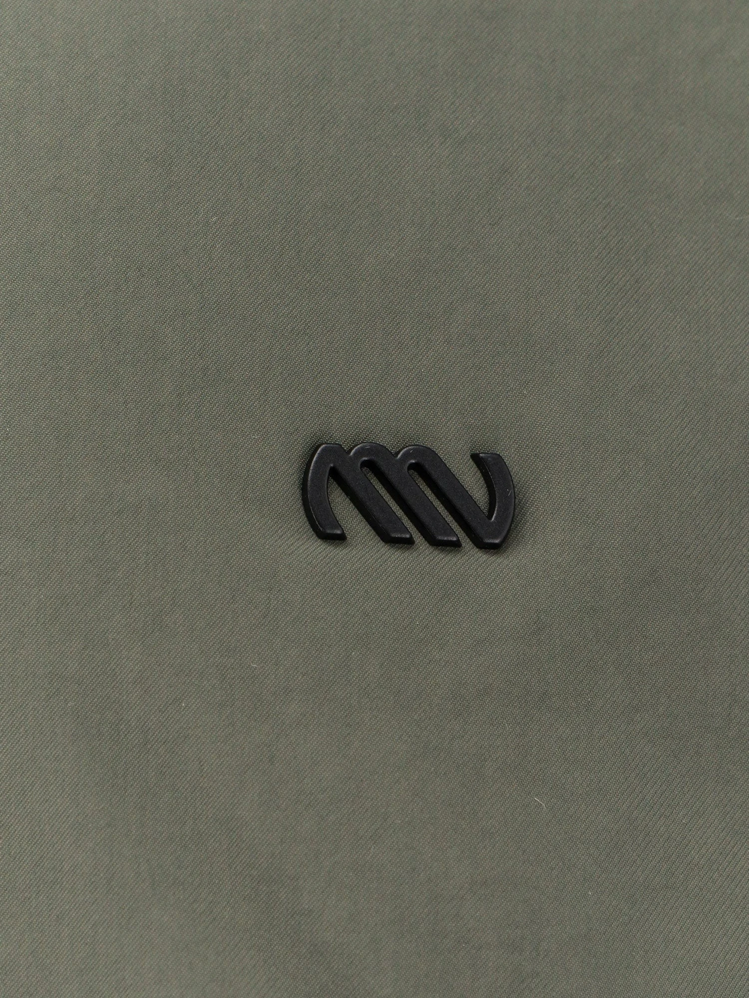 Nylon jacket with metal logo patch on the front.webp