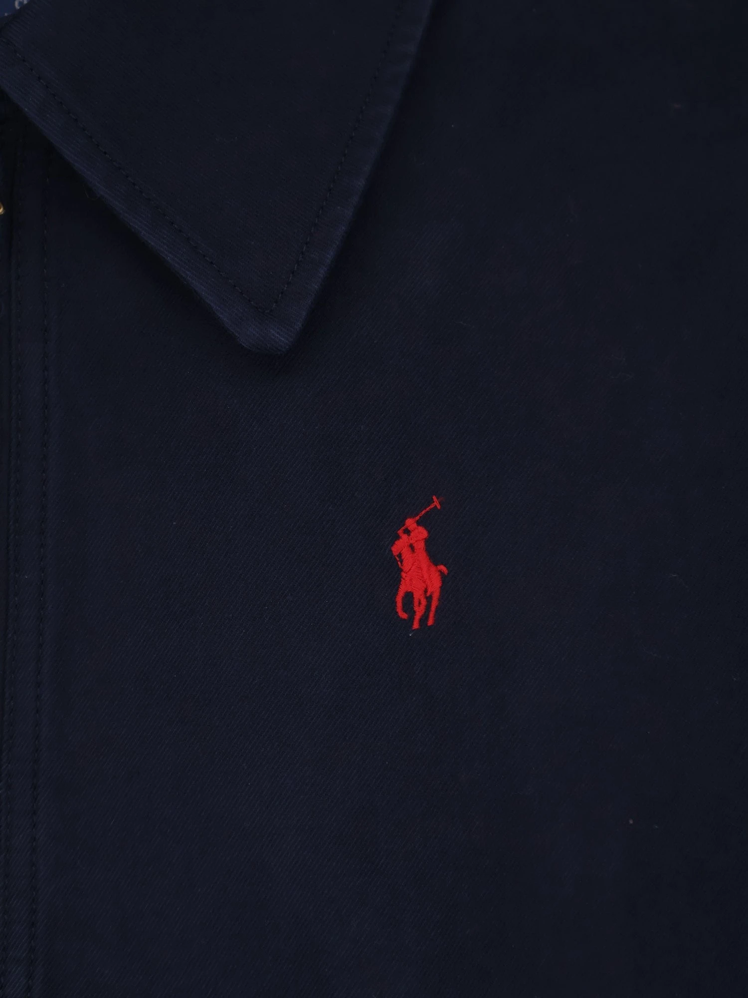 Blue denim jacket with embroidered logo on the front.webp