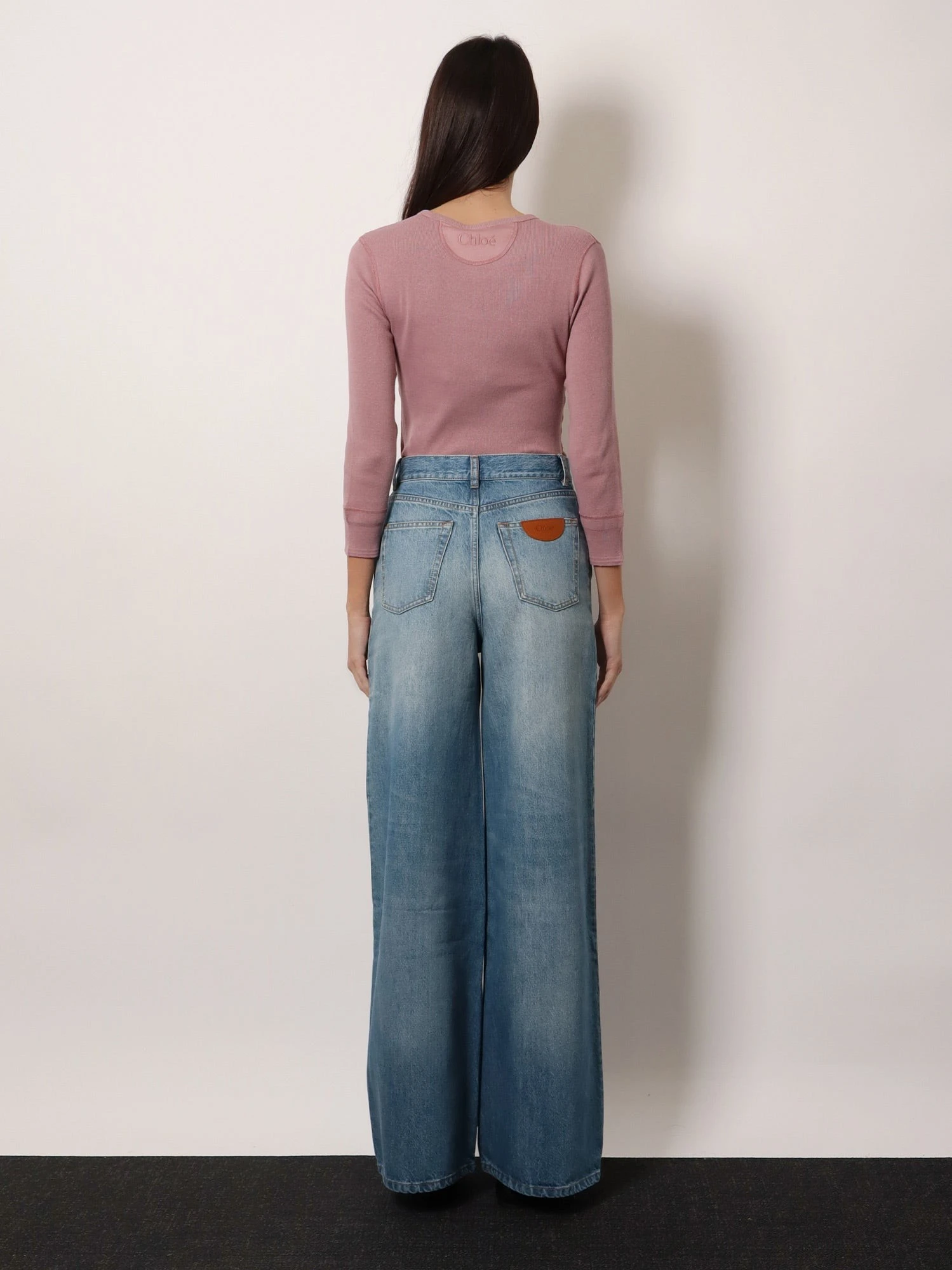 Blue denim jeans with logo label on the back.webp